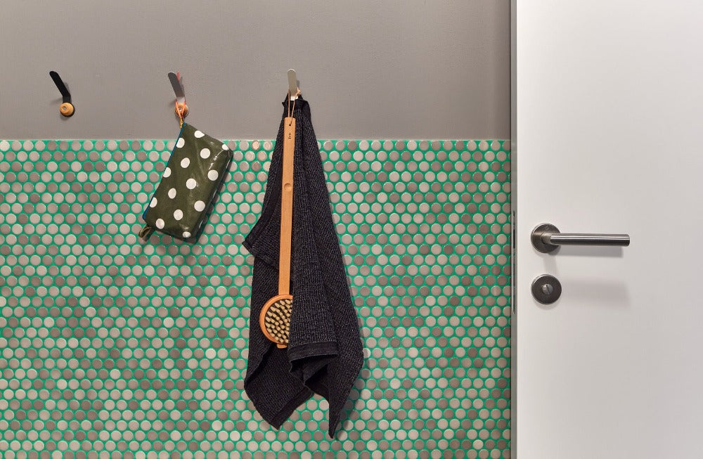 Modwalls PopDotz Porcelain Penny Round Tile | 1” Gloss | Mocha Blend | Brown | Pictured installed on a bathroom wall with green grout | Colorful Modern & Midcentury tile for bathrooms, kitchens, backsplashes, showers, floors, pools & outdoors.