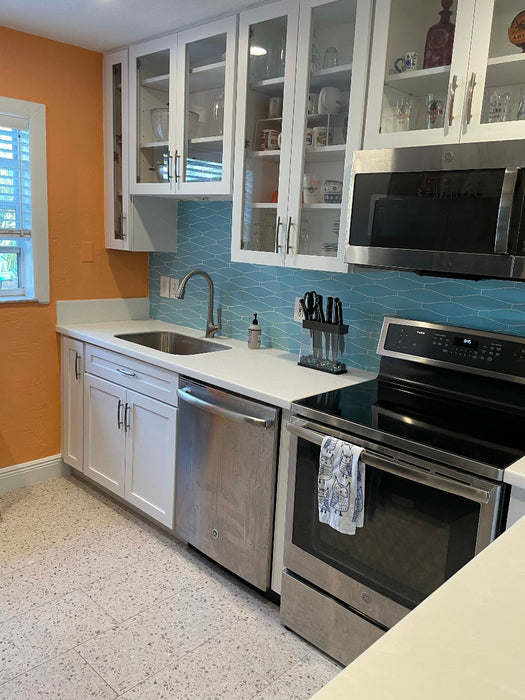 Our summer sky blue kiln minnow ceramic tile is highlighted in this modern kitchen with terrazzo floors and bright orange accent walls. white cabinets and stainless steel appliances give it a clean modern look. This unique ceramic tile is hand crafted in 105 colors and is great for kitchens, baths and feature areas.