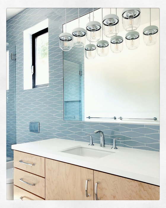 A minnow shaped tile in a soft watery blue gives a peaceful and bright feeling to this bathroom. Kiln Ceramic Minnow Tile is hand crafted in 105 colors and is perfect for kitchens, baths & backsplashes.