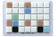 A square sample card showing a grid of small color tiles on a white backing, with the brand name modwalls printed near the bottom. The tiles include white, light blue, tan, green, black, and blue-gray colors.