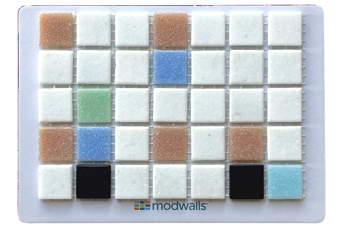 A square sample card showing a grid of small color tiles on a white backing, with the brand name modwalls printed near the bottom. The tiles include white, light blue, tan, green, black, and blue-gray colors.